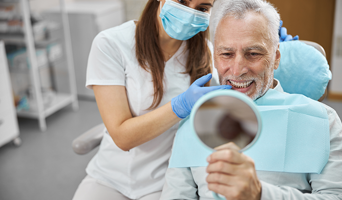 Image of a man looking at his smile after a dental implant placement, at Greashaber Dentistry in Ann Arbor, MI.