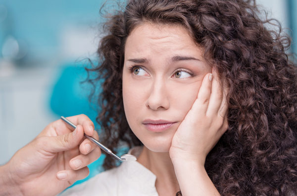 Woman holding cheek due to tooth ache.